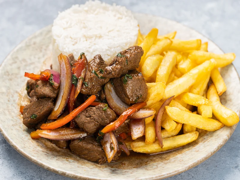 Lomo saltado péruvien, sauté de bœuf aux oignons et tomates servi avec frites et riz